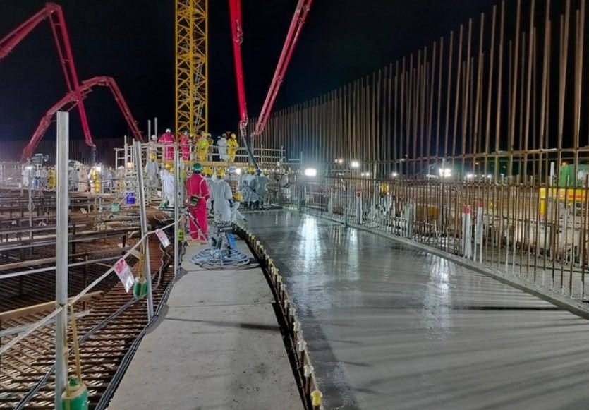 Night shot of a curved rebar corridor with crew in colored PPE