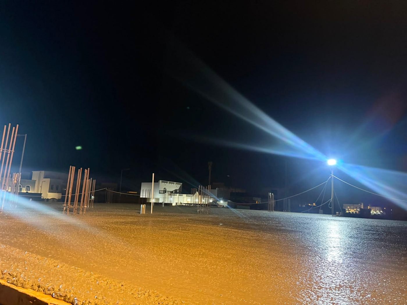 Freshly poured concrete slab lit by floodlights at night