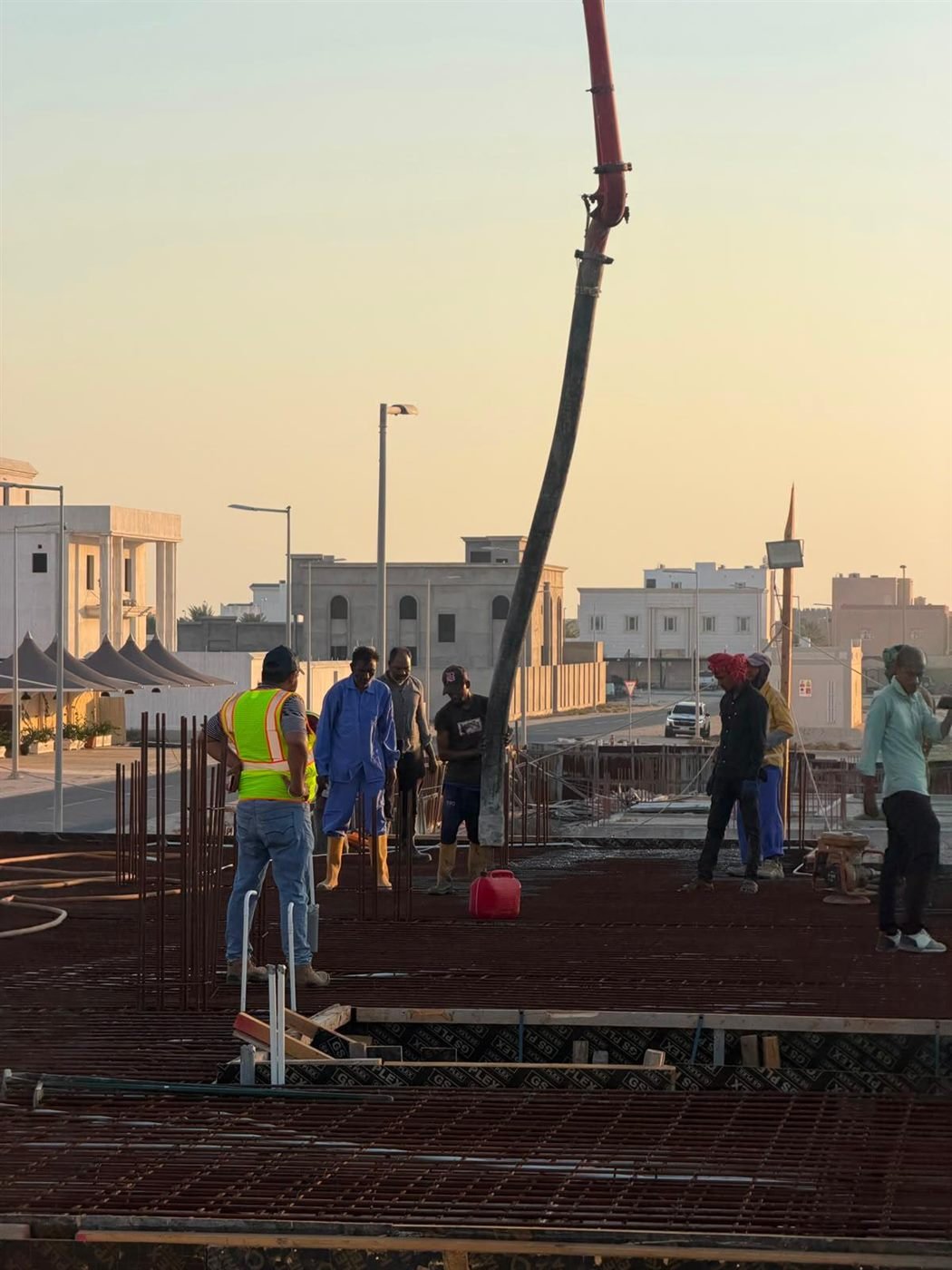 Wide view of an active site with concrete pump boom and crew
